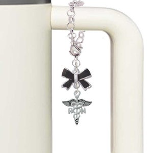 May include: A silver charm with a black bow and a silver medical caduceus charm with the letters RN. The charm is attached to a silver chain.