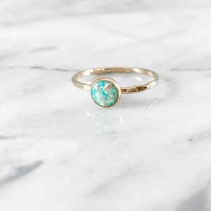 Könnte beinhalten: Ein zarter Goldring mit einem gehämmerten Band und einem runden, hellblauen Opal-Edelstein.