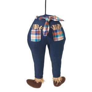 Könnte beinhalten: Eine blaue Jeanshose mit karierten Taschen und einer karierten Schleife. Die Jeans hat braune Stoffschuhe mit Strohelementen.