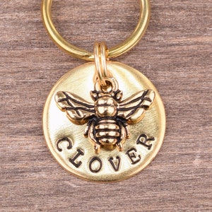May include: Gold-toned pet ID tag with a bee charm and the word "CLOVER" engraved on the front.