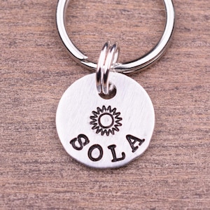 May include: Silver key ring with a round tag that says "SOLA" with a sun design above the word.