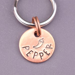 May include: A copper key chain with a silver key ring. The copper tag has the word "PEPPER" engraved on it with a small chili pepper graphic.