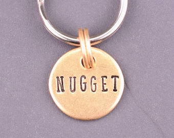 May include: A silver keyring with a round brass tag that says "NUGGET" in all caps.