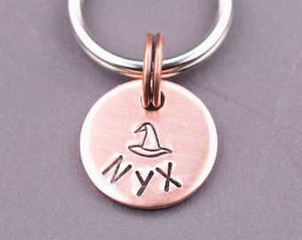 May include: A copper key chain with a silver ring and a charm that says "NYX" with a witch's hat above the name.