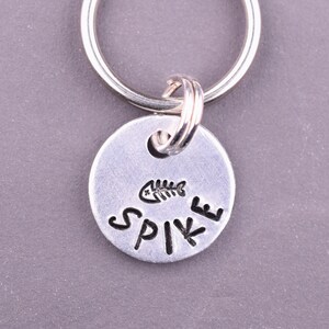 May include: Silver key ring with a round tag that says "SPIKE" with a small fishbone icon above the text.
