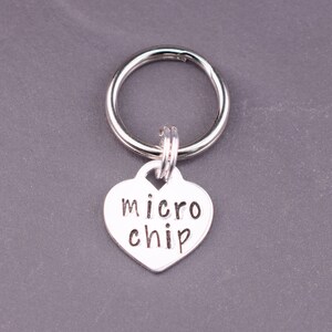 May include: Silver heart-shaped charm with the text "micro chip" attached to a silver key ring.