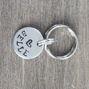 May include: Silver key ring with a round tag that says "BELLE" with a heart above the "E".