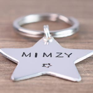 May include: Silver star-shaped keychain with a ring attached. The star has the name "MIMZY" engraved on it.