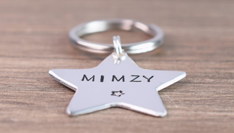 May include: Silver star-shaped keychain with a ring attached. The star has the name "MIMZY" engraved on it.