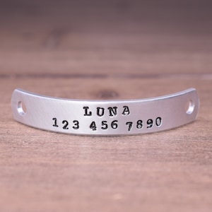 以下が含まれることがあります： 「LUNA」という名前と「123 456 7890」という番号が刻まれた銀色の金属タグです。