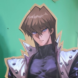 Könnte beinhalten: Ein Papp-Ausschnitt eines Charakters aus der Anime-Serie Yu-Gi-Oh! Der Charakter trägt einen schwarzen Rollkragenpullover, einen langen schwarzen Mantel mit weißen Akzenten und einen schwarzen Gürtel. Der Charakter hat braunes Haar und blaue Augen.