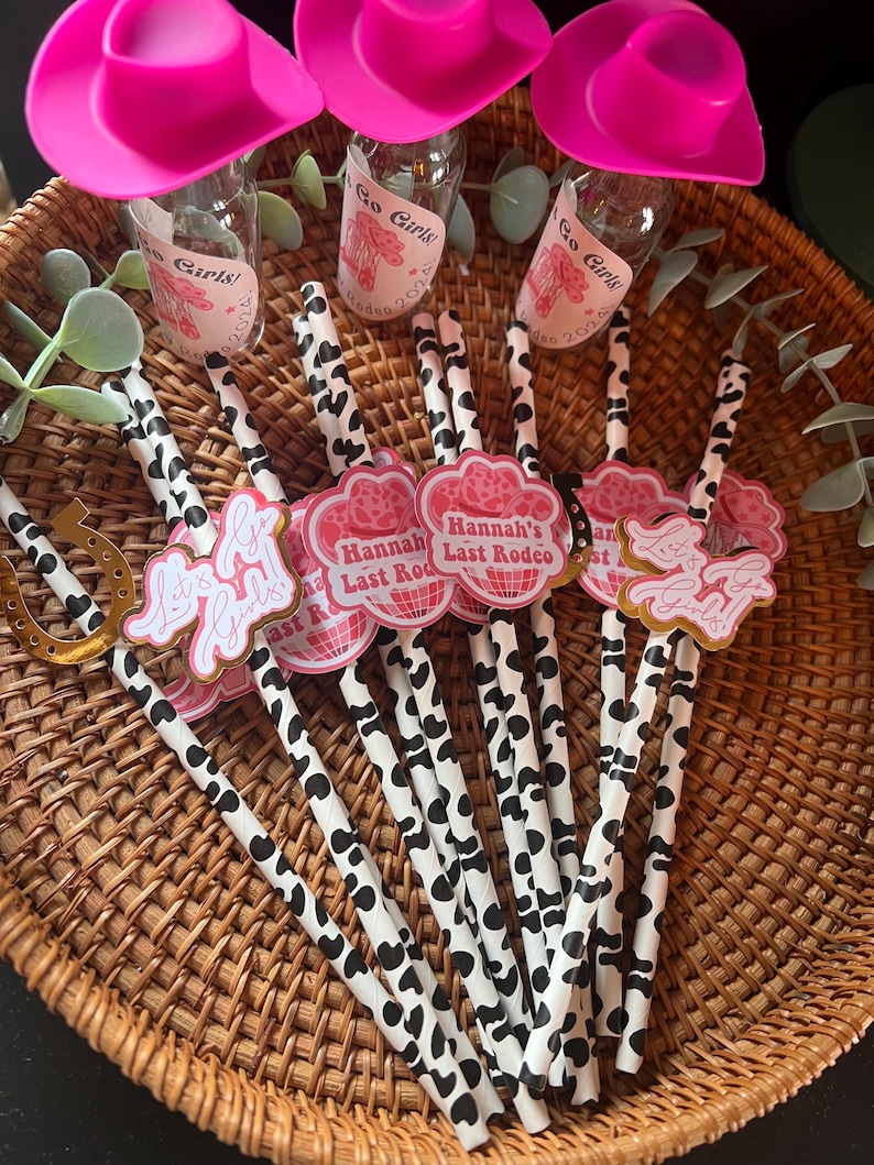 May include: A set of 10 black and white striped paper straws with pink and gold cowgirl themed toppers. The toppers feature the text "Let's Go Girls!" and "Hannah's Last Rodeo".