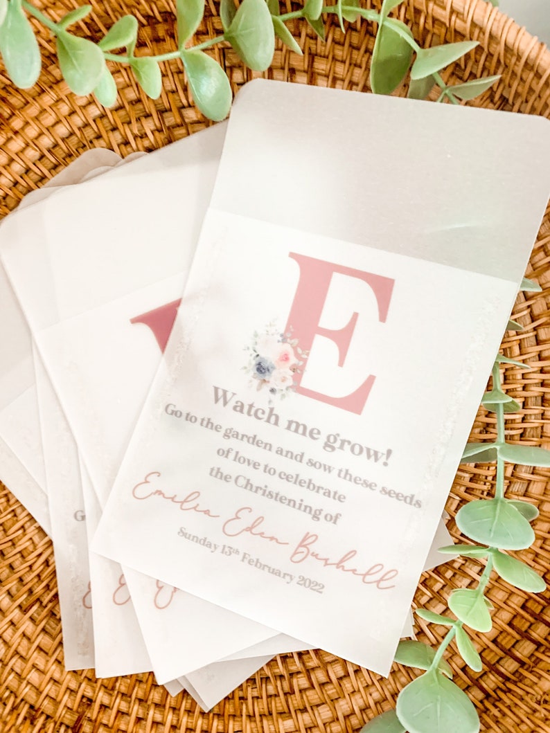 Puede incluir: Una tarjeta blanca con una letra E rosa y un dise&ntilde;o floral. La tarjeta dice "Watch me grow! Go to the garden and sow these seeds of love to celebrate the Christening of Emelia Eden Bushell Sunday 13th February 2022".