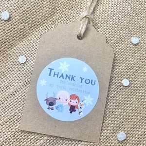 May include: A brown paper thank you tag with a blue and white circle sticker featuring the characters from Frozen. The sticker says "Thank You for sharing my royal celebration".