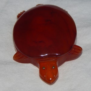 May include: A red plastic turtle figurine with gold eyes. The turtle is a vintage item and has a glossy finish.