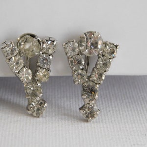 May include: A pair of silver tone clip-on earrings with a cluster of clear rhinestones in a Y shape.