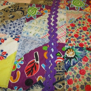 May include: A patchwork quilt with a variety of colorful fabrics and patterns. The quilt is made with different shapes and sizes of fabric, and it is sewn together with a purple ribbon. The quilt is a beautiful example of handmade craftsmanship.