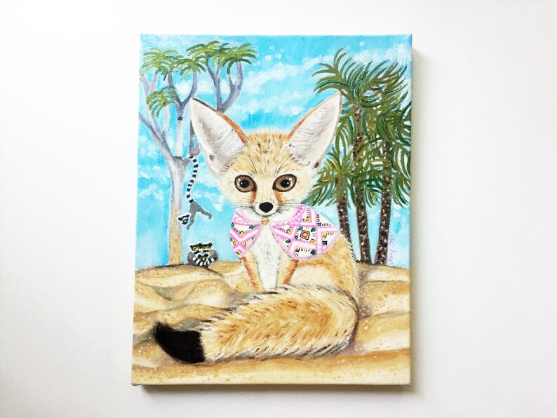 May include: A painting of a fennec fox wearing a pink and white patterned scarf. The fox is sitting in the sand with palm trees and a blue sky in the background.