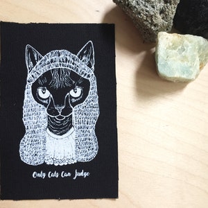Peut inclure: Illustration en noir et blanc d'un chat portant une robe de juge et une perruque. Le texte "Only Cats Can Judge" est sous l'image.