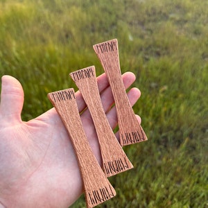 Peut inclure: Trois nœuds papillon en bois avec une teinte brun foncé. Chaque nœud papillon a un motif différent de lignes verticales gravées dans le bois.