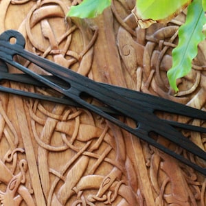 May include: Two dark brown wooden hair sticks with a circular design at each end, resting on a carved wooden surface. The hair accessories have a sleek, minimalist design, perfect for various hairstyles.