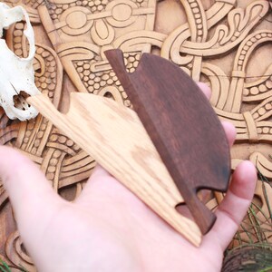 May include: Two wooden, hand-carved bottle openers. One is light-colored, the other is dark brown. The openers are held over a carved wooden surface with a skull in the background. The background has a carved, Celtic knot design.