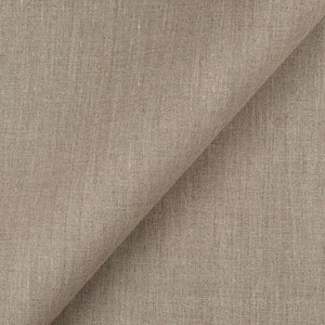 Puede incluir: Primer plano de una tela de lino beige con una textura sutil tejida. La tela est&aacute; doblada por la mitad, creando una l&iacute;nea diagonal a trav&eacute;s de la imagen.