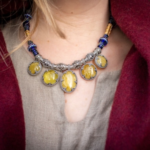 May include: A silver necklace with blue and gold beads and five yellow gemstone pendants.