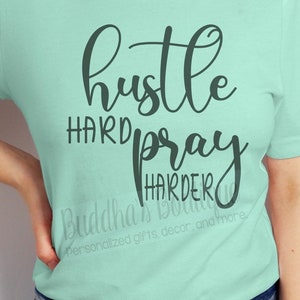 May include: A light green t-shirt with the text "hustle hard pray harder" in black cursive lettering.