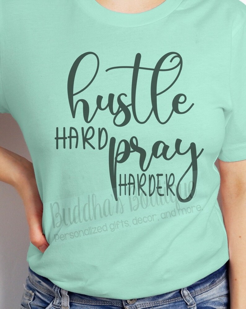 May include: A light green t-shirt with the text "hustle hard pray harder" in black cursive lettering.