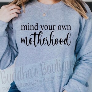 以下が含まれることがあります： 黒い文字で「mind your own motherhood」と書かれた灰色のスウェットシャツ