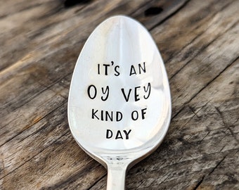 May include: A silver spoon with the phrase "It's an Oy Vey kind of day" engraved on the front.