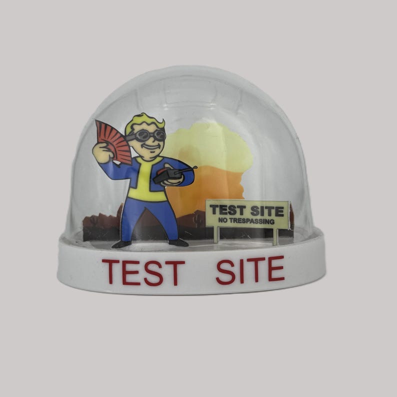 May include: A clear snow globe with a cartoon character holding a fan and a device. The base is white with the words "TEST SITE" in red. A sign reads "NO TRESPASSING".
