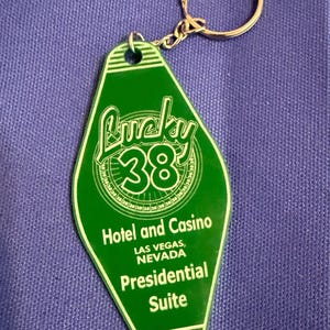 May include: Green vintage-style keychain with the text "Lucky 38 Hotel and Casino, Las Vegas, Nevada, Presidential Suite." The keychain has a gold-colored ring and chain.