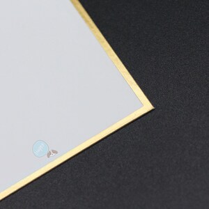 May include: A white card with a gold border and a small blue and brown graphic in the corner. The card is set against a black background.