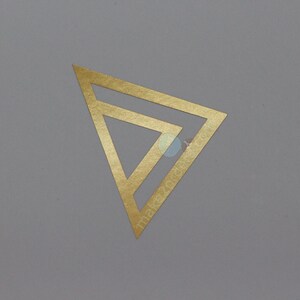 May include: A gold-coloured geometric design, featuring a layered triangle shape, is centred on a grey background. The text "makezotik" is visible on the design. The overall aesthetic is minimalist and modern.