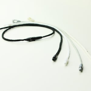 Puede incluir: Cinco tipos diferentes de cuerda con puntas de plástico. Las cuerdas son negras, blancas y crema.