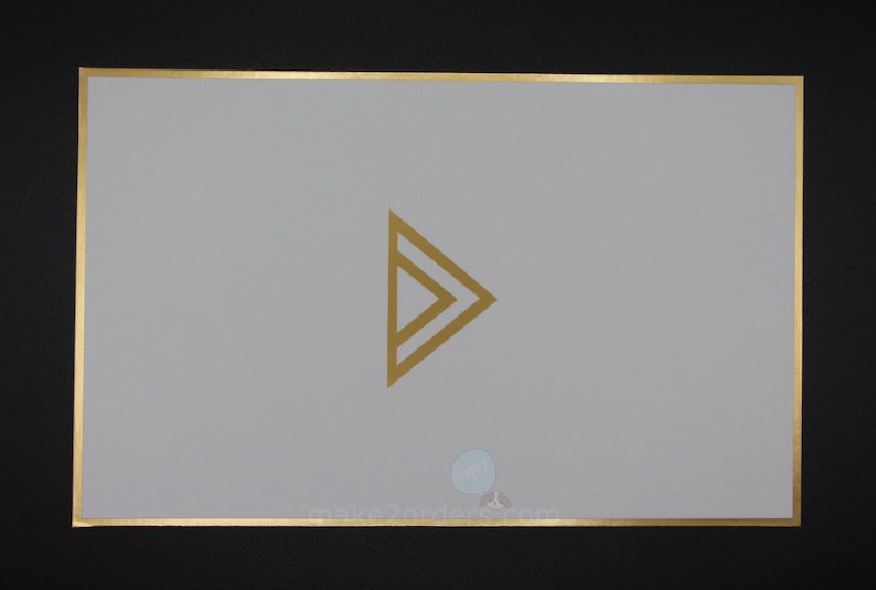 May include: A rectangular card with a gold border and a gold geometric arrow design in the centre. The card is light grey, and the background is black. The website address make2orders.com is at the bottom.