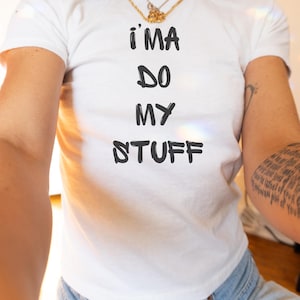 May include: White t-shirt with black text that reads "I'MA DO MY STUFF".
