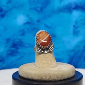 ladies ring size 5 1/4 the stone is a 18 x 13  mm Onyx Agate.  heavy duty blossom band. It is bordered by 2 leaves and a blossom.