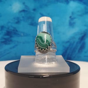 May include: A silver ring with a green and white agate stone set in a decorative silver bezel.
