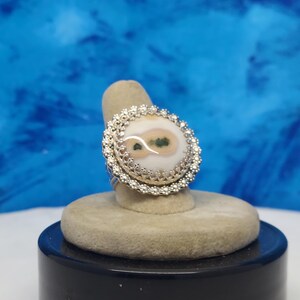 May include: A silver ring with a white and green agate stone set in a filigree design.
