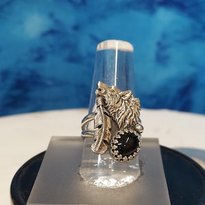 May include: A silver ring with a wolf head design, a feather, and a black onyx stone.