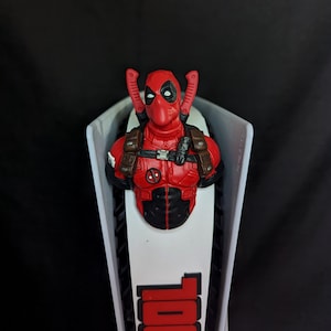May include: A white and black beer tap handle with a red Deadpool figure on top. The handle has the word "POOL" printed on it in red.