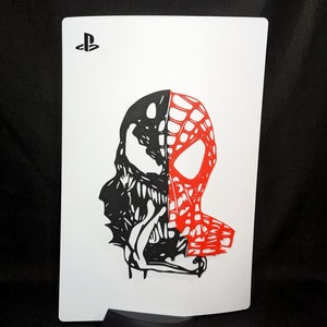 May include: A white card with a black PlayStation logo in the top left corner. The card features a black and red silhouette of a character with a web design on the right side of the face and a menacing expression on the left side of the face.