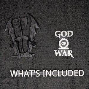 May include: Black 3D-printed decorative set featuring a stylized axe and swords, the words "GOD OF WAR", and the phrase "WHAT'S INCLUDED" in white. The items are arranged on a textured black surface.