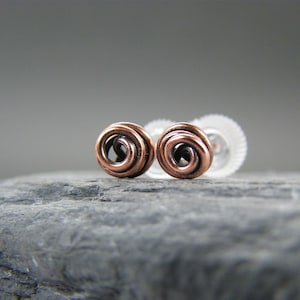 以下が含まれることがあります： 螺旋状のデザインの銅線イヤリングのペア。イヤリングは灰色の背景の上にあります。