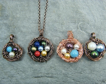 May include: Four copper wire nests with different colored beads inside. The nests are hanging from a chain, and the beads are a mix of blue, green, white, and brown.