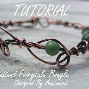 May include: Copper wire wrapped bracelet with green gemstone beads. The bracelet is designed in a vine pattern. The text "Woodland Fairytale Bangle Designed By Annemarie" is below the bracelet.