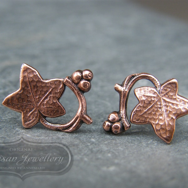 May include: A pair of copper earrings featuring a hammered ivy leaf design with small berry accents.